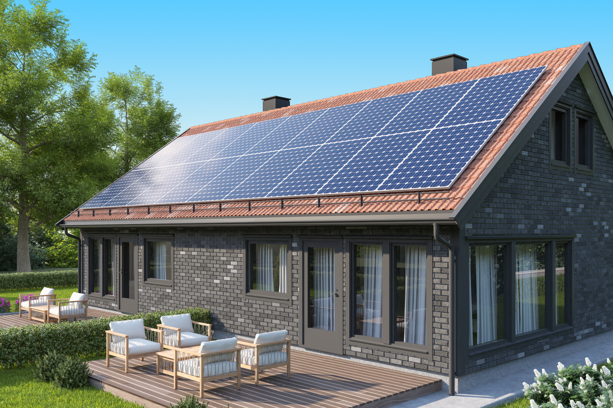 Grande toiture inclinée d'une maison en brique entièrement couverte de modules photovoltaïques