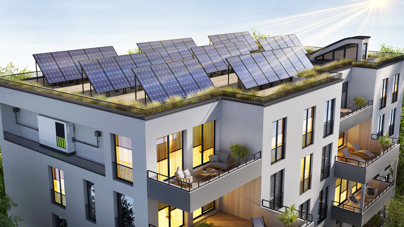 Immeuble contemporain avec toiture-terrasse végétalisée et champ de modules photovoltaïques sur structures inclinées