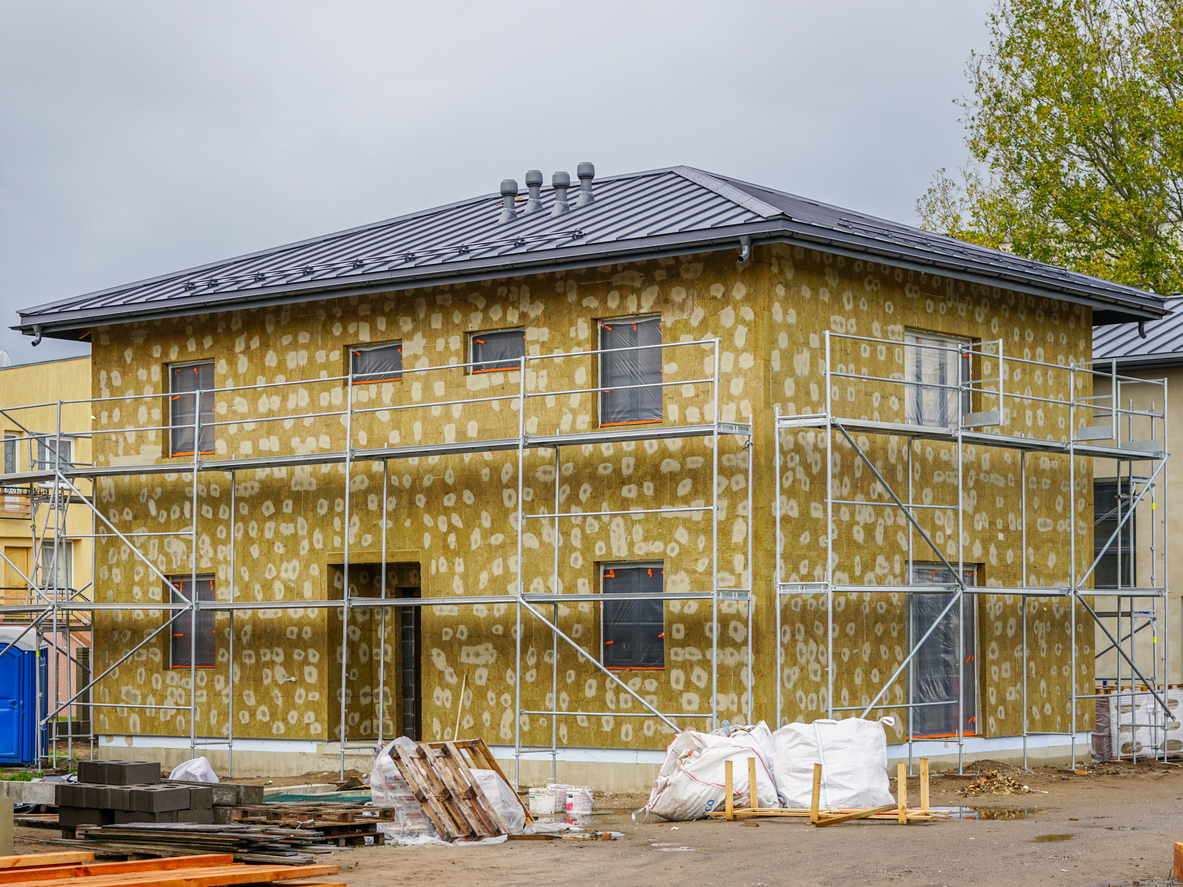 Bâtiment sous échafaudage recouvert de laine minérale pendant son isolation extérieure
