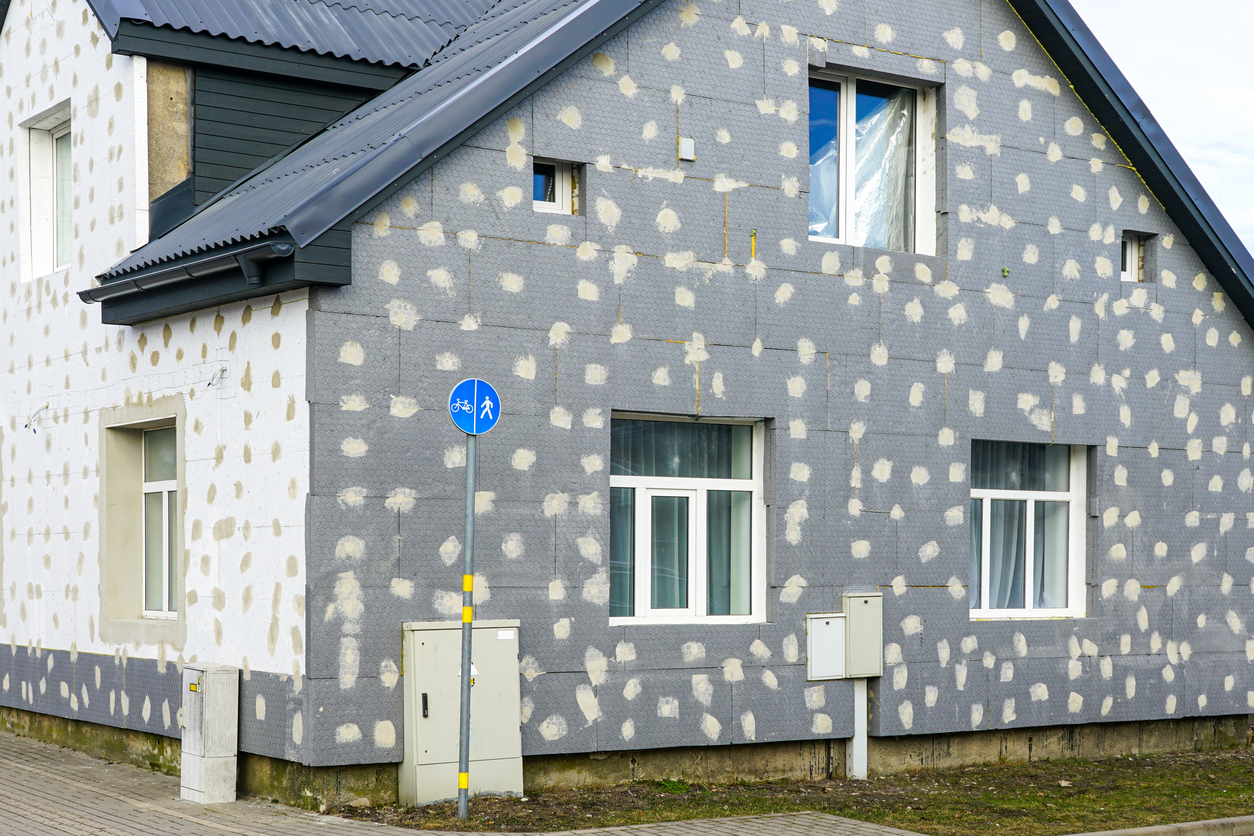Façade de maison recouverte de panneaux de polystyrène avec plots de colle visibles