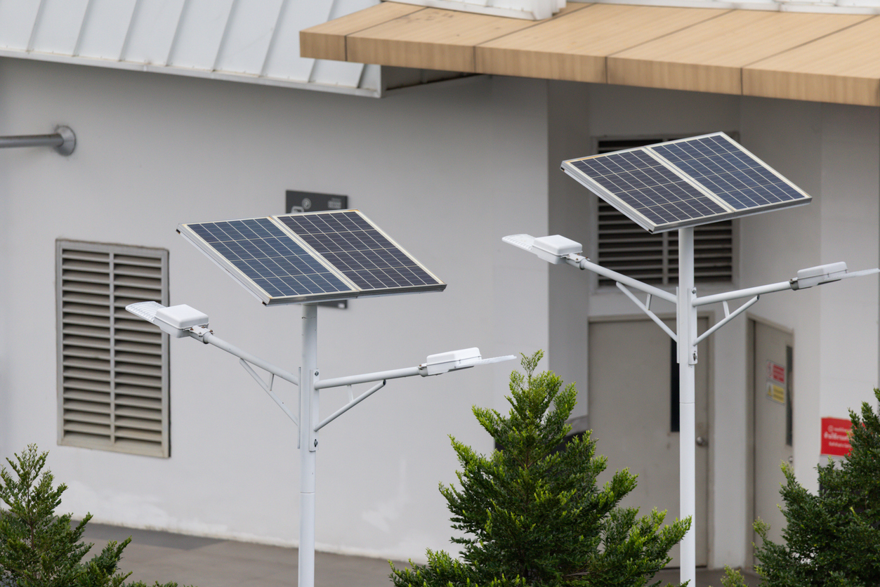 Deux mâts d'éclairage solaire autonome à double projecteur devant un bâtiment technique