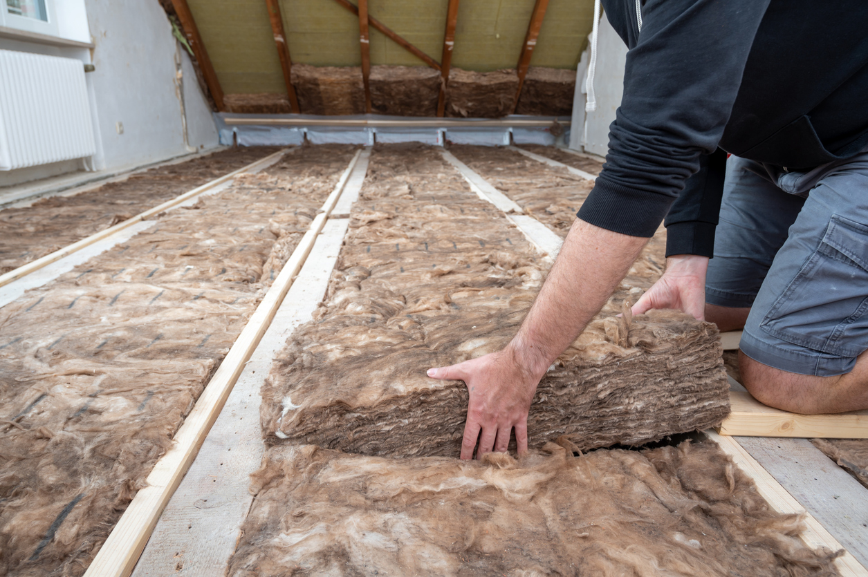 Pose d'un panneau de laine de bois en deuxième couche croisée sur un plancher de combles