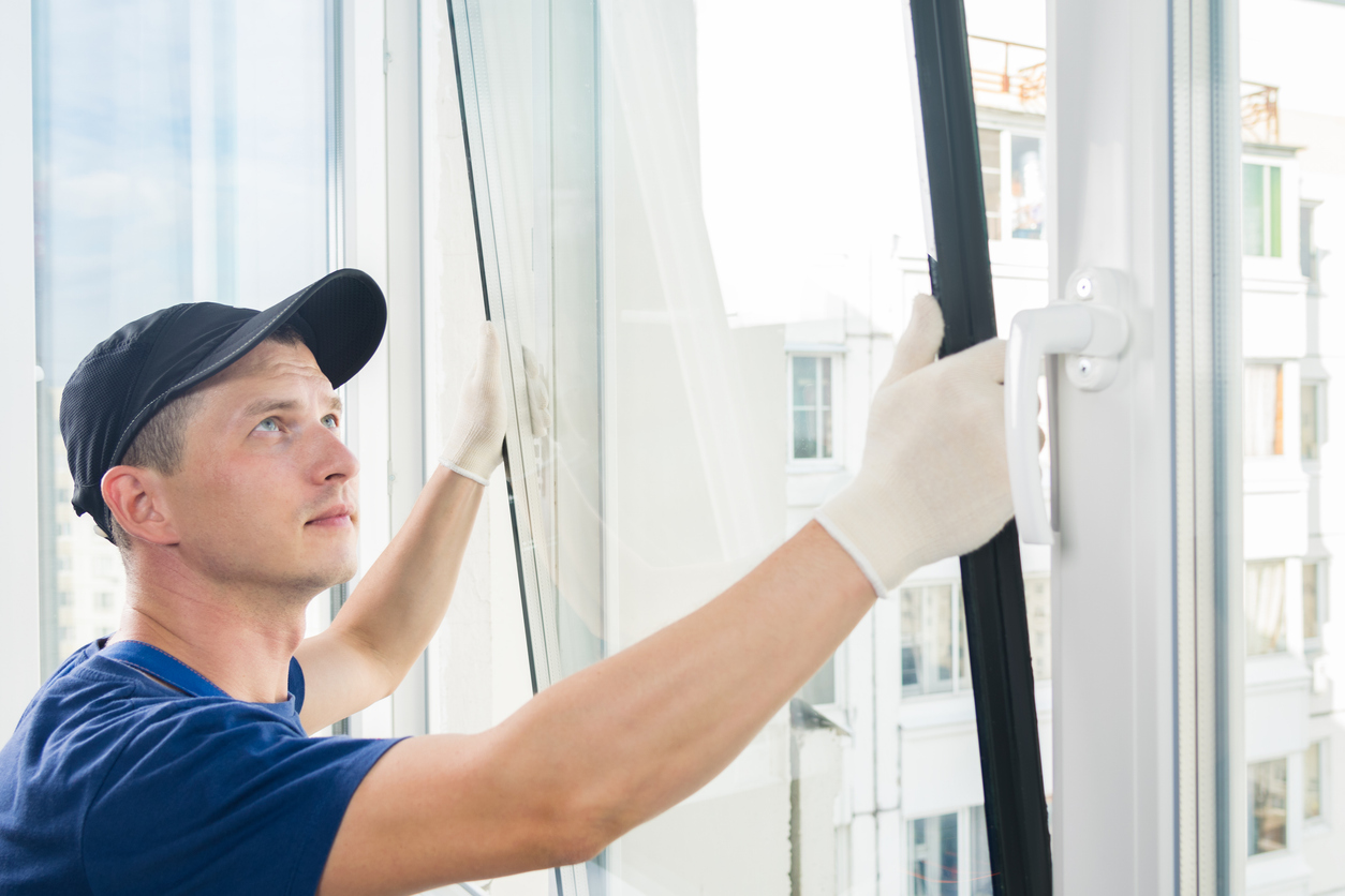 Poseur ajustant un ouvrant vitré sur une fenêtre d'appartement