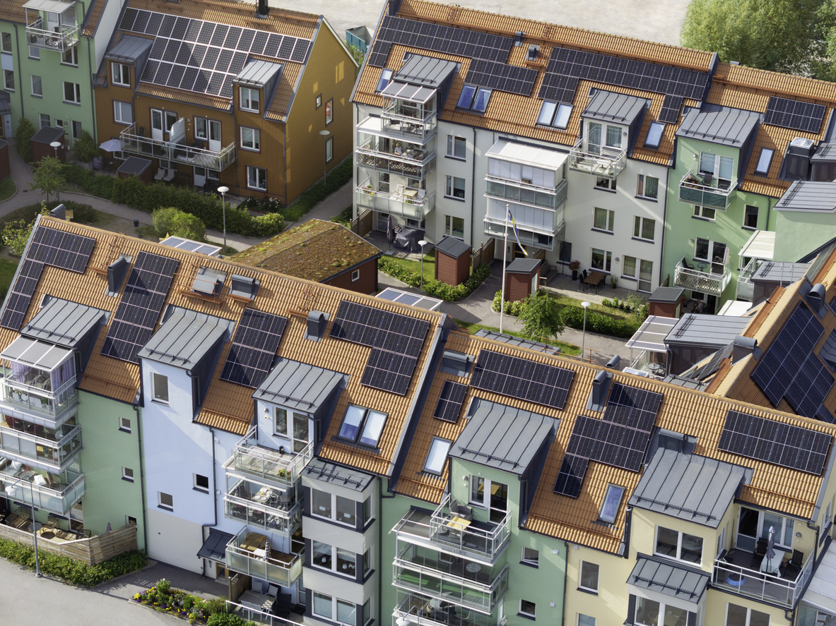 Vue aérienne d'un quartier de logements collectifs aux toitures en tuiles équipées de champs photovoltaïques