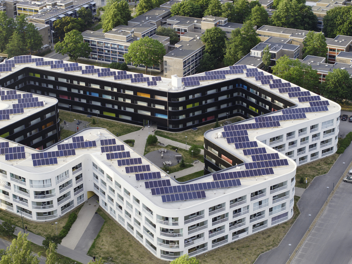 Vue aérienne de résidences collectives dont les toitures-terrasses sont équipées de rangées de modules photovoltaïques