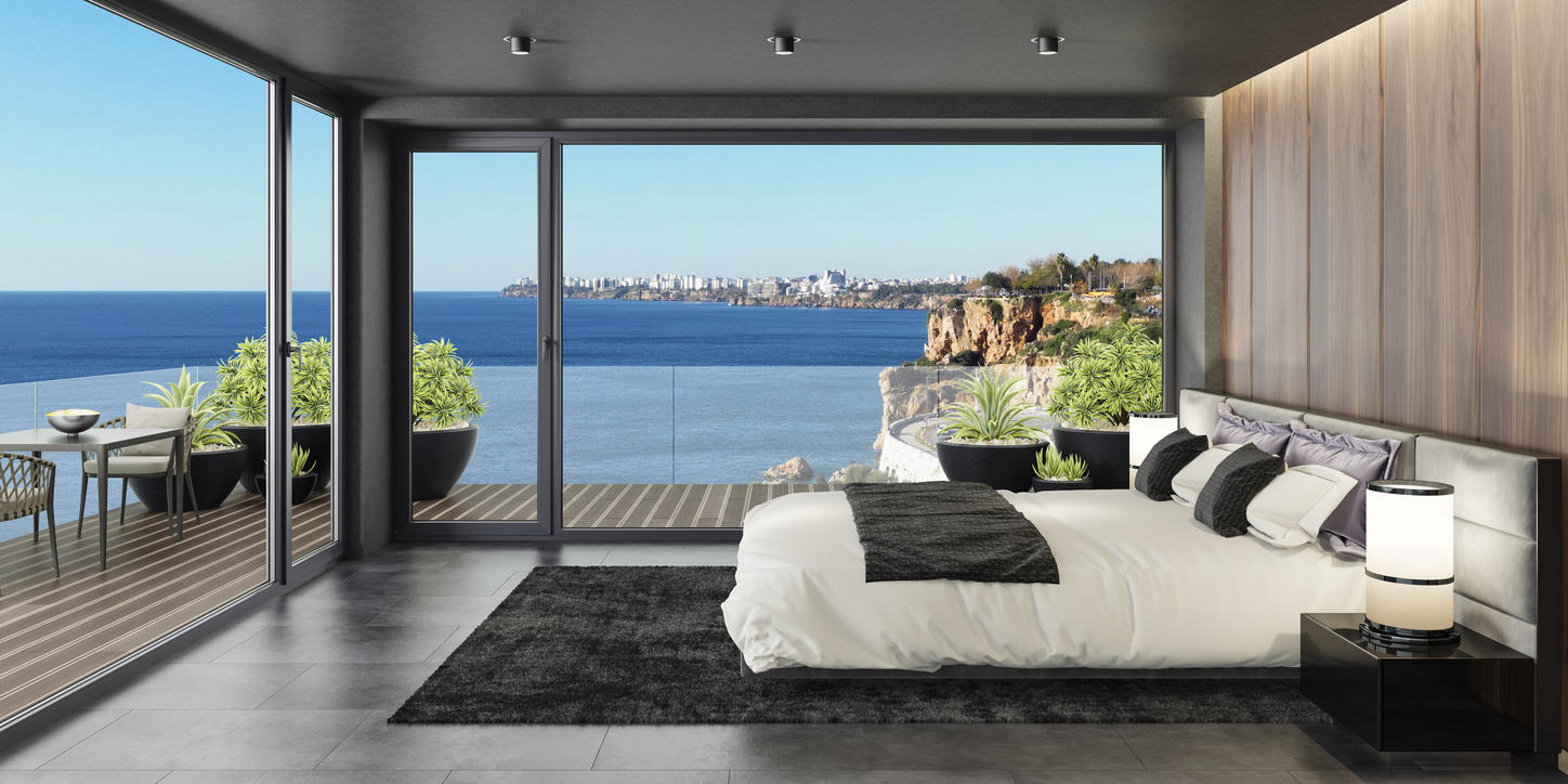 Chambre ouverte sur une terrasse par une baie vitrée coulissante panoramique avec vue mer