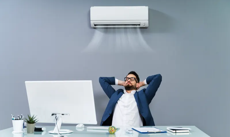 Occupant sous un split mural en appartement — climatisation réversible immeuble d’habitation dans l'Aube