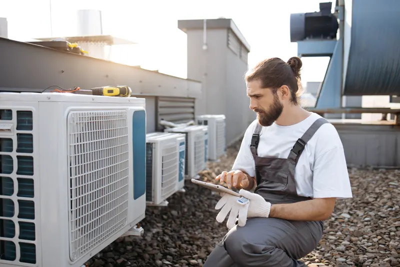 Technicien contrôlant les groupes extérieurs en toiture — climatisation réversible immeuble d’habitation dans l'Aube
