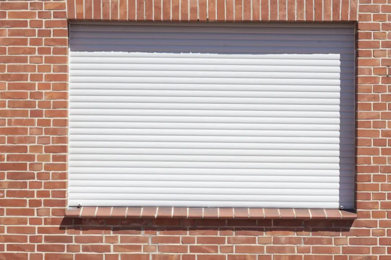 Volet roulant blanc sur façade en brique — en Bretagne