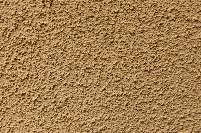 Détail d'un enduit de façade projeté, texture grattée