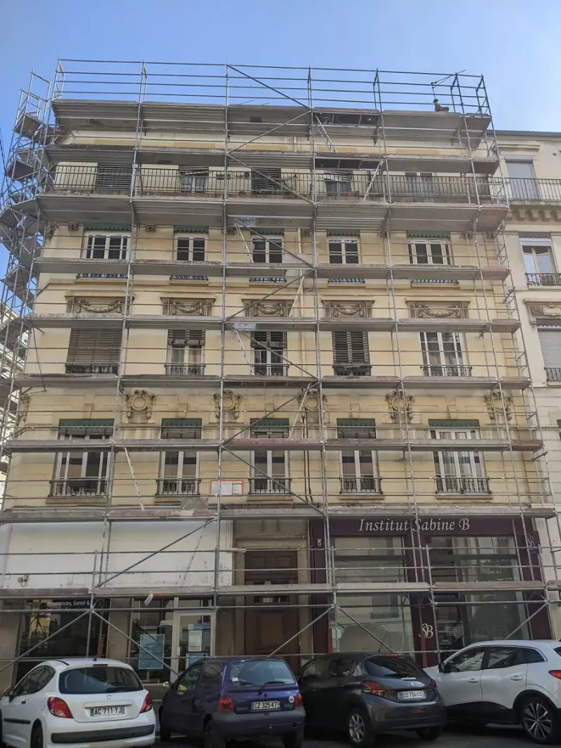 Immeuble d'angle entièrement bâché et échafaudé pendant un ravalement de façade